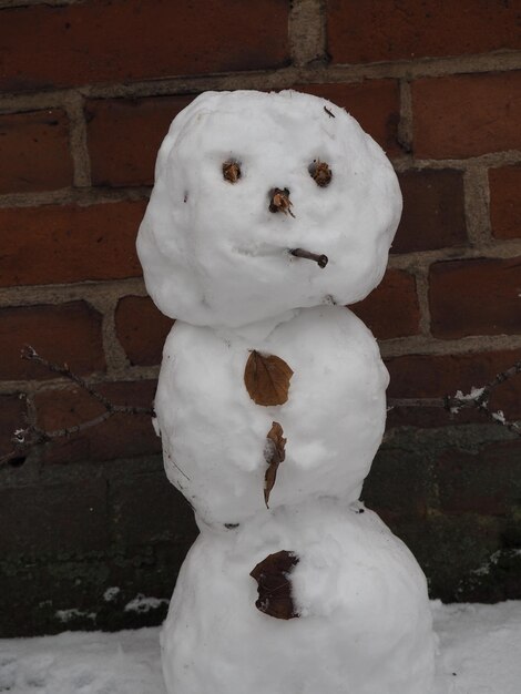 Photo close-up of snowman in yard against brick wall