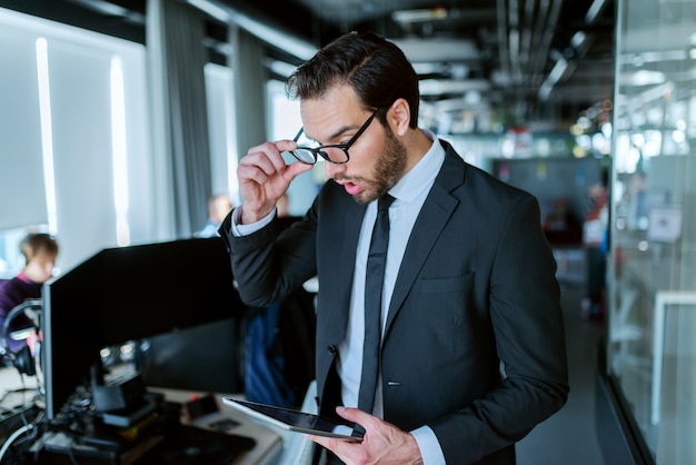 Chiuda in su dell'avvocato di successo calzino vestito in abbigliamento formale in piedi davanti al suo ufficio e utilizza la tavoletta per il lavoro.