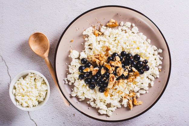 Close up of soft cottage cheese with blackcurrant and walnuts on a breakfast plate top view