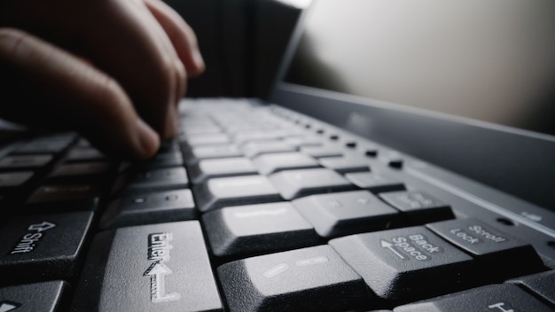 Close-up soft-focus finger typing on keyboard.