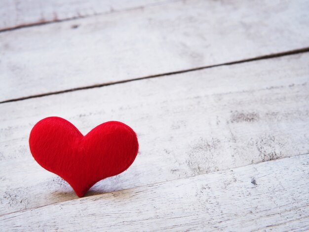 Close up soft red heart shape on white old wooden table.