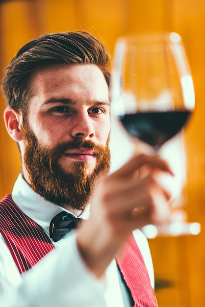 Foto sommelier in primo piano che tiene il vino in bicchiere