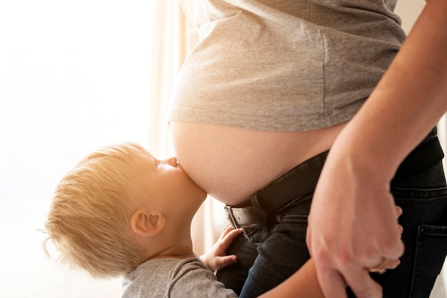 Figlio del primo piano che bacia la pancia incinta della madre