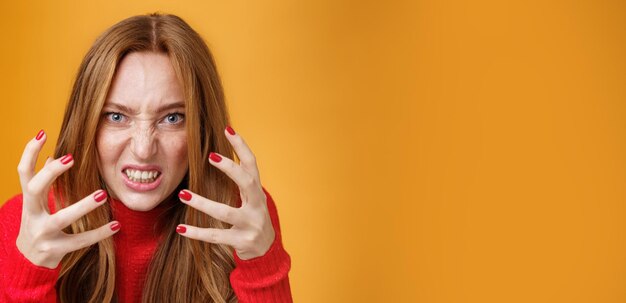 Foto close-up sot van pissige en boze roodharige vrouw die handen opsteekt en ze balde van woede en verontwaardiging