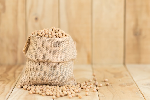 Close up soy beans in sack on wooden desk