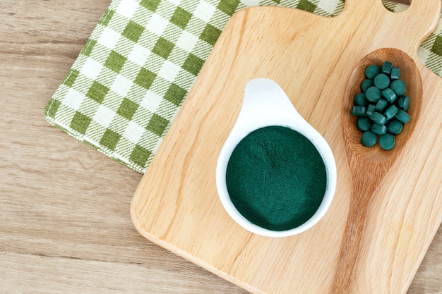 Chiuda sulla polvere di spirulina in pillole della spirulina e della ciotola in cucchiaio, in dieta superfood sana e nel concetto di nutrizione della disintossicazione