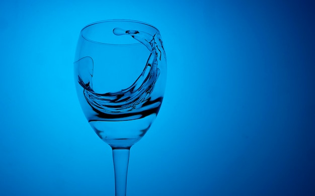 Close-up of splashing water in glass against blue background