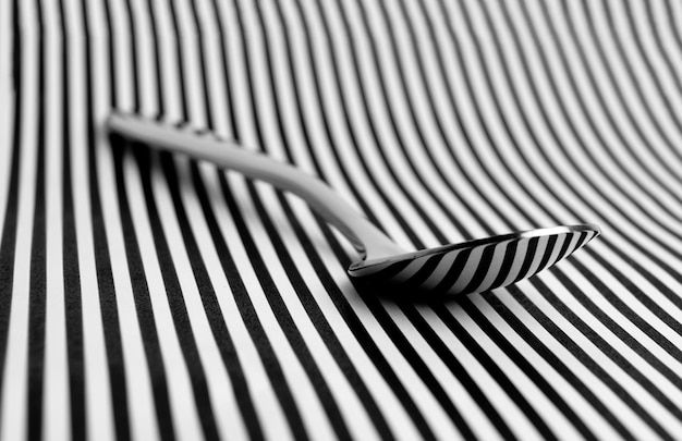 Photo close-up of spoon on white and black striped table