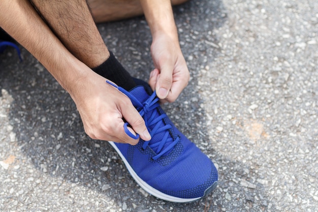 Close-up of sportsman. He tying sneakers on running shoes before practice.