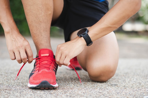 Foto close-up di uno sportivo che si lega le scarpe e si prepara a iniziare a praticare il concetto di stile di vita sano