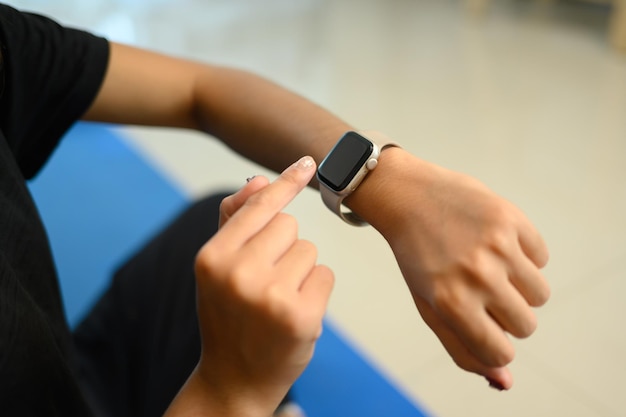 close up sportswoman using a smartwatch to monitor her health or workout progress