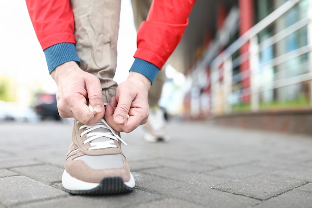 Close-up of sporty male person hands tying up shoelace.