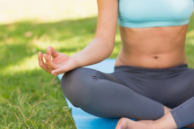 Close-up of a sporty woman in lotus pose at park