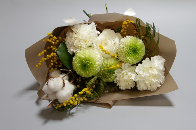 Close-up spring bouquet of mimosa branch, chrysanthemum, ranunculus, cotton, carnation , selective focus