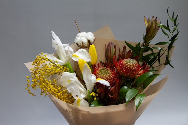 Close-up spring bouquet of ruscus, leucadendron, leucospermum, iris, cotton, mimosa branch, tulip , selective focus