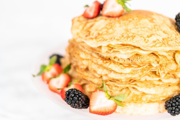 Photo close up. stack of freshly baked crepes with berries on a cake stand.