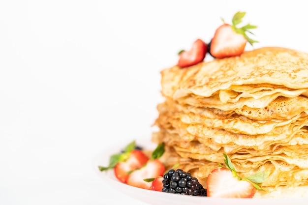 Close up. Stack of freshly baked crepes with berries on a cake stand.