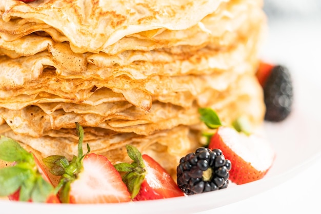 Close up. Stack of freshly baked crepes with berries on a cake stand.