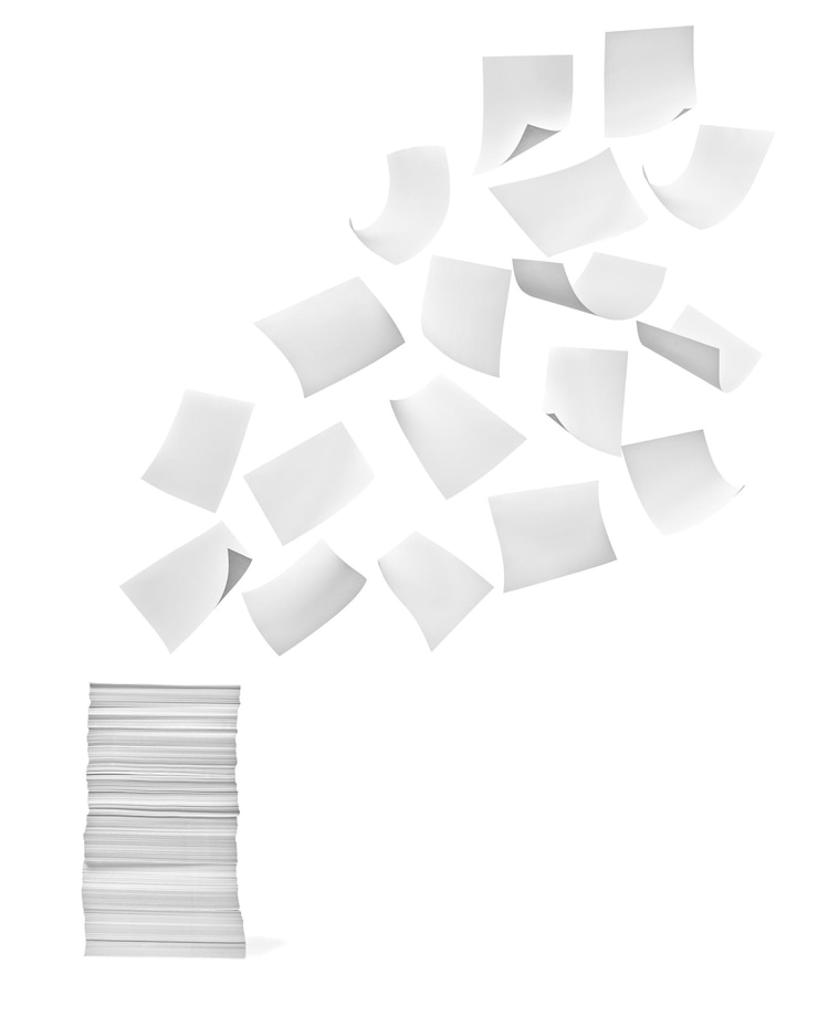 Photo close up of a stack of paper and flying papers on white background