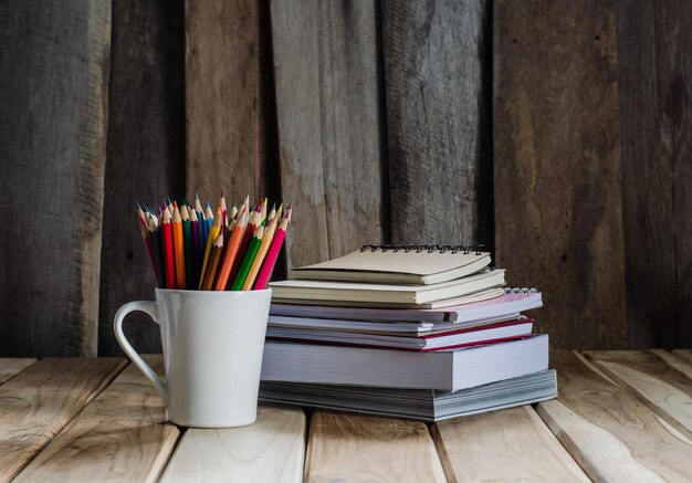 Photo close-up of stacked books with colored pencils on table