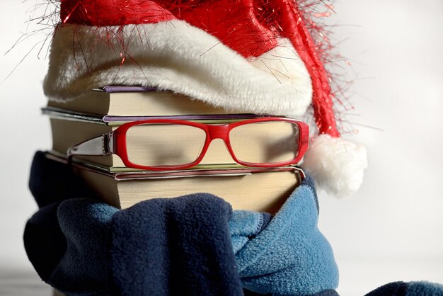 Foto close-up di libri impilati con occhiali e cappello di babbo natale sullo sfondo bianco