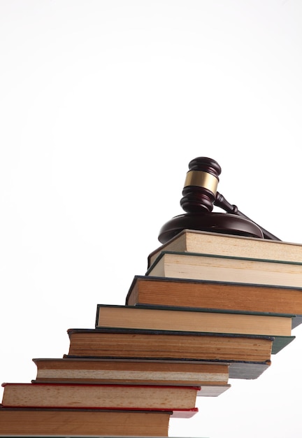 Close-up of stacked books with gavel against white background