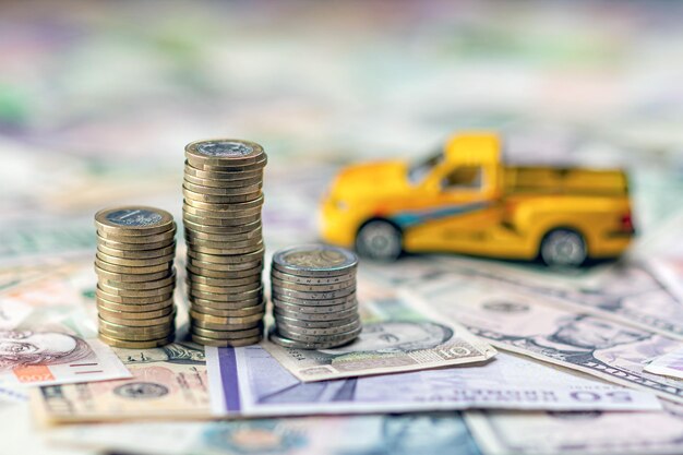 Close-up of stacked coins by toy car on paper currency at table