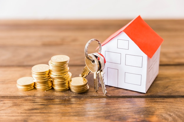 Photo close-up of stacked coins, house and key on wooden desk