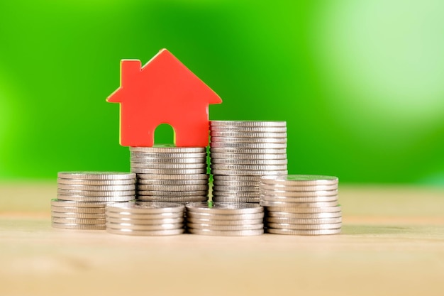 Photo close-up of stacked coins with model house on table