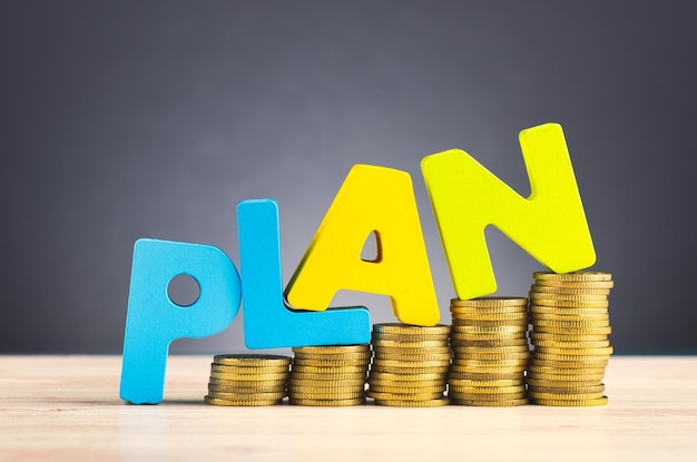 Close-up of stacked coins with plan text on table against gray background