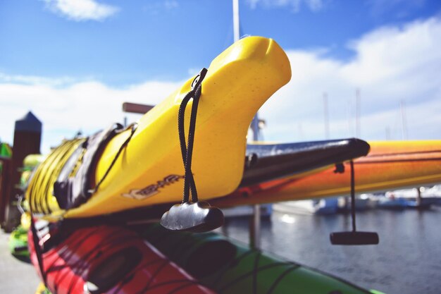 Close-up of stacked kayaks at lakeshore on sunny day