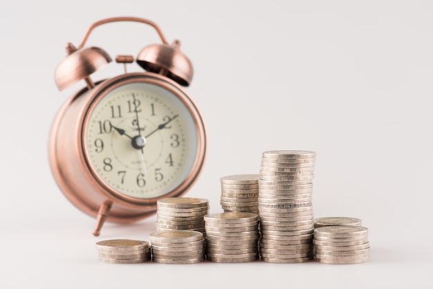 Close up of stacking gold coins with alarm clock, Business Finance and Money concept