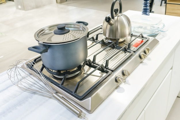 Close-up of stainless steel cooking pot and kettle boiling on gas stove in kitchen