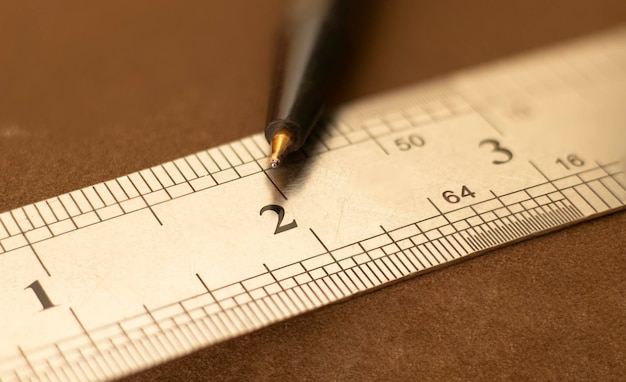 Close up of a stainless steel scale r ruler showing a Two inch point with pen Selective focus isolated on Dark