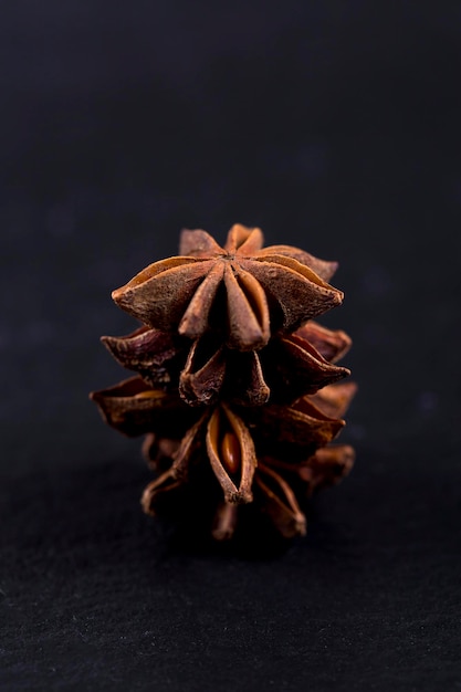 Close-up of star anise tower on black background. Pile of star anise seeds on black stone. Dark background