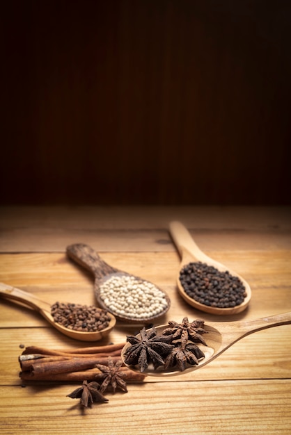 Close up Star anise in wooden spoon surround with spice powder on wooden table