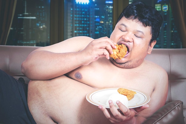 Close up of starving fat man eating fried chicken