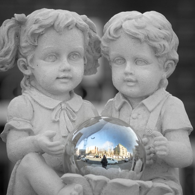 Photo close-up of statues with crystal ball reflected city street