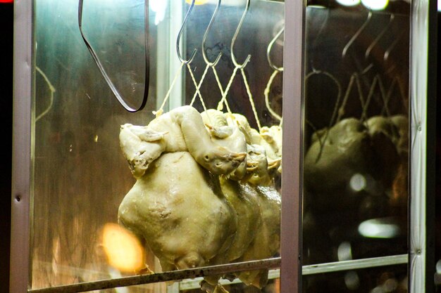 Foto close-up di polli al vapore appesi a una bancarella di cibo di strada