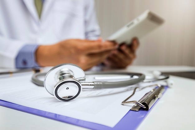 Close-up of stethoscope is lying on the clipboard in front of  a doctor.