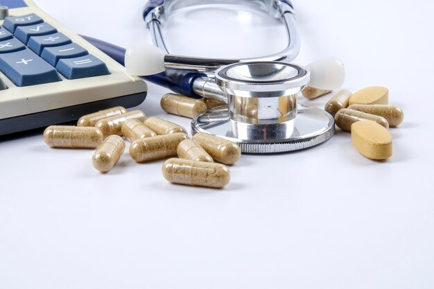 Photo close-up of stethoscope with calculator and medicines over white background