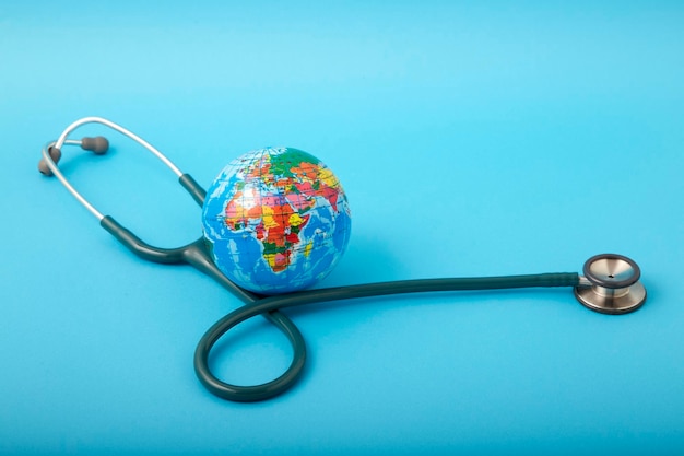 Photo close-up of stethoscope with globe over blue background