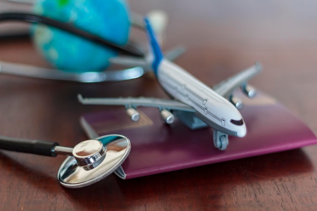 Foto close-up di uno stetoscopio con un modello di aereo e un passaporto sul tavolo