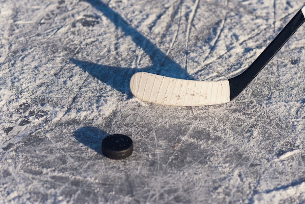 Close-up stick and puck on the ice background