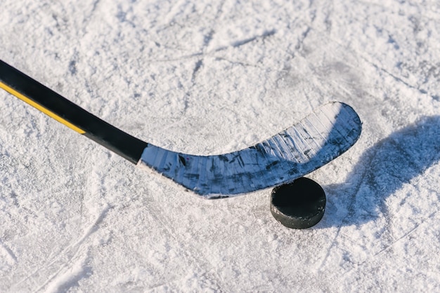 Close-up stick and puck on the ice background