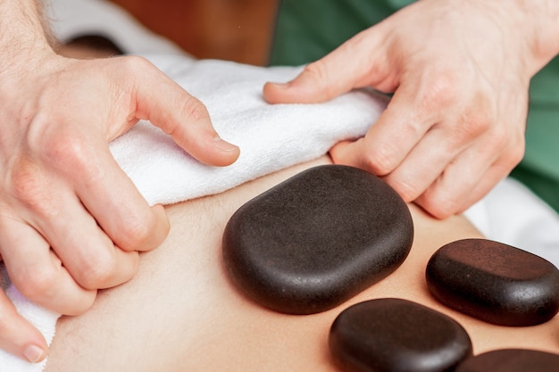 Close up on stone massage on back of man