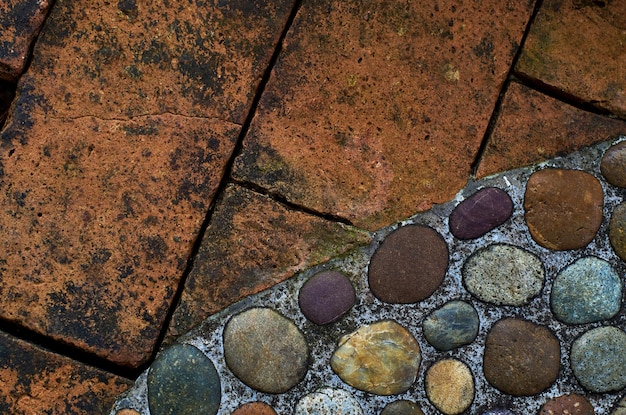 赤レンガの壁といくつかの小さな石のある石道の接写。
