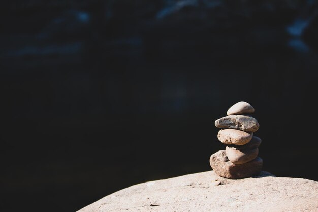 Foto close-up di una pila di pietre sulla roccia su uno sfondo nero