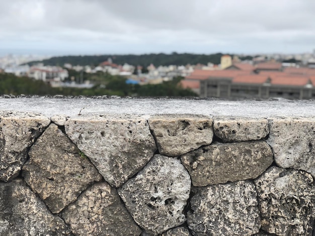 Close-up of stone wall by building against sky