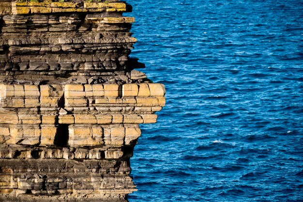 Foto close-up di strati di formazione rocciosa con il mare sullo sfondo